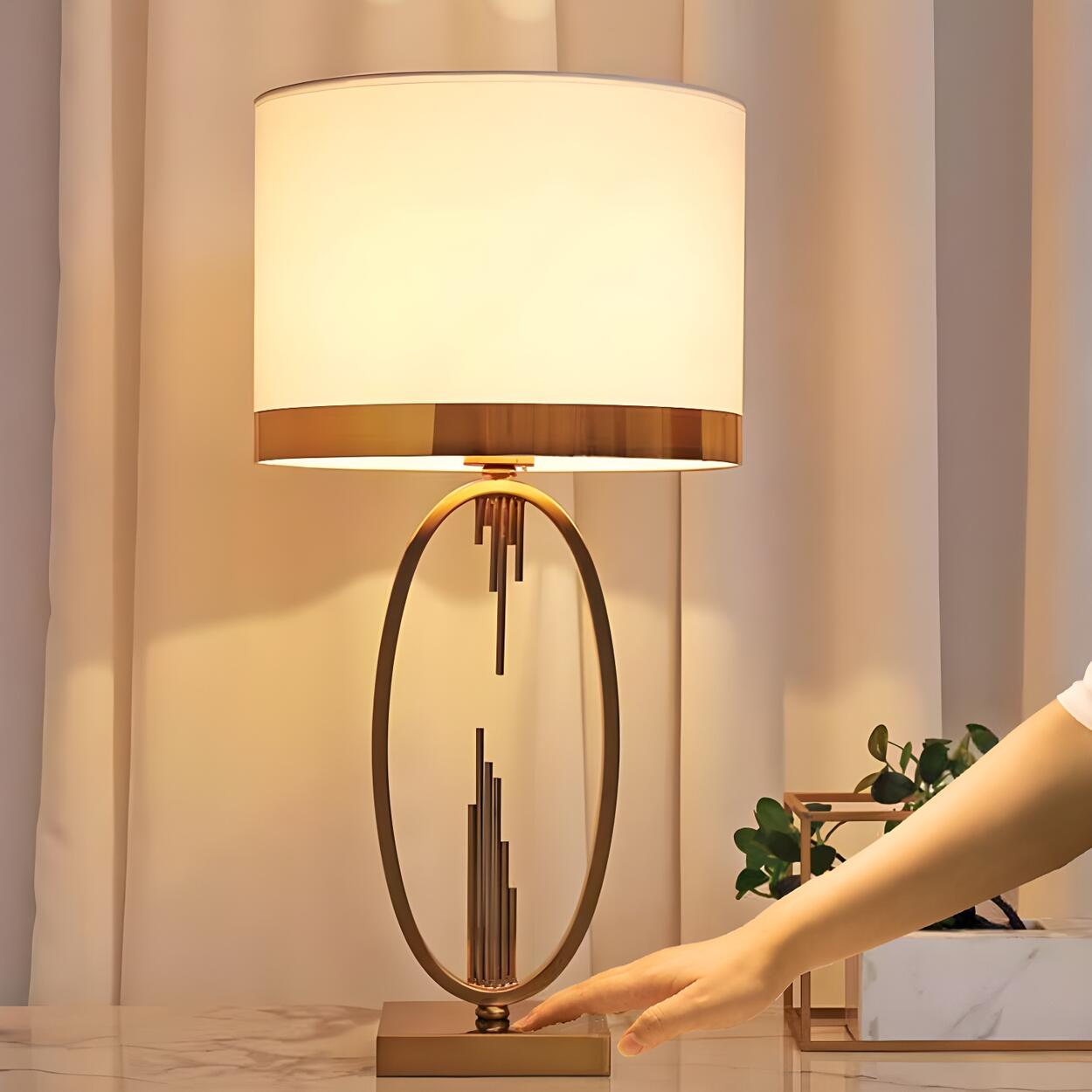 Elegant bordslampa med oval ram i guld och vit tygskärm